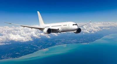 Airplane flying above coastline and ocean