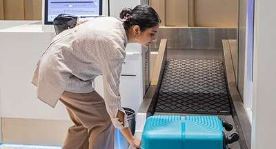 Passenger placing suitcase on baggage belt