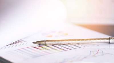 Pen placed on financial report with charts and graphs