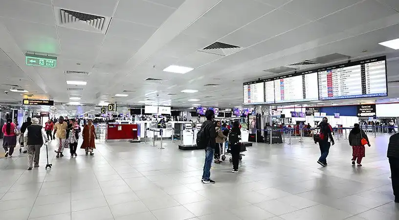 Airport terminal check-in hall with passengers and flight information displays