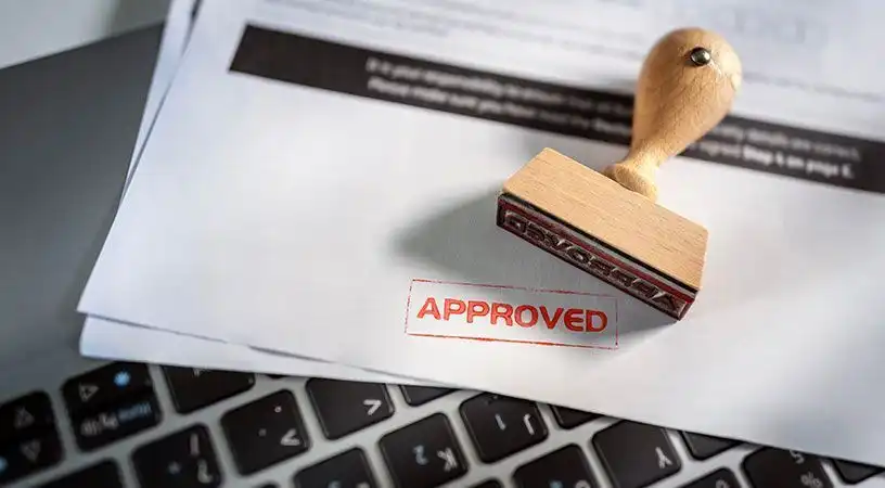 Official document stamped “Approved” placed on a laptop keyboard