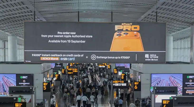 Large overhead digital billboard inside busy airport concourse